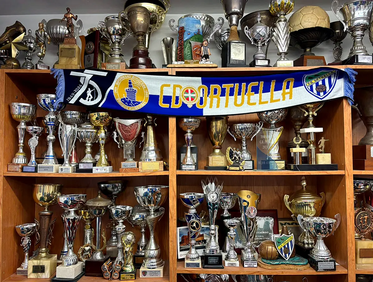 Vitrina de trofeos del club con la bufanda del 75 aniversario y el escudo del Ortuella
